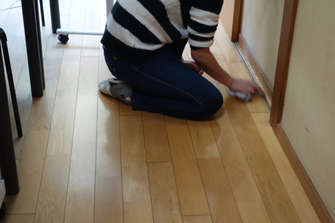 床の隅々まで丁寧に掃除する女性