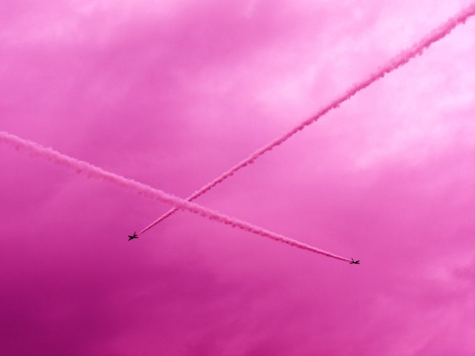ピンク色のスモークを出しながら空を飛ぶ飛行機
