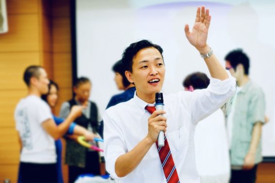 http://マイクを持って案内をする青井代表